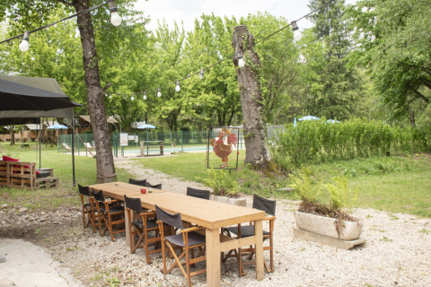 Espace repas extérieur avec table en bois et chaises, entouré de verdure au Camping Pittoresque, Occitanie.