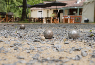 Bocce da pétanque sul campo di ghiaia al Camping Pittoresque, villaggio vacanze in Occitania, Francia.
