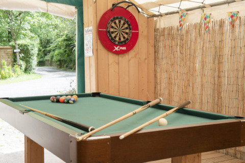 Zona de juegos al aire libre en Camping Pittoresque, Occitania, con mesa de billar y tablero de dardos.