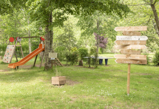 Parco giochi e cartelli in legno al Camping Pittoresque, parco vacanze in Occitania, Francia.