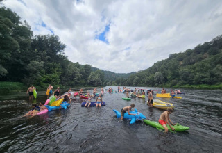 Persone galleggiano su gonfiabili colorati sul fiume al Camping Pittoresque in Occitanie, Francia.