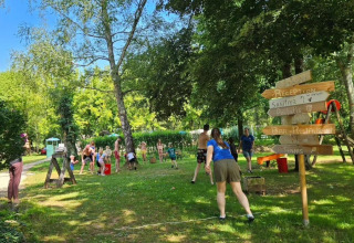 Familier leger udendørs på en grøn campingplads i skyggen ved Camping Pittoresque i Occitanie, Frankrig.