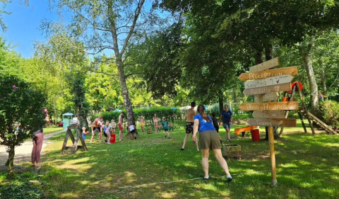 Familias jugando al aire libre en la zona verde y sombreada de Camping Pittoresque en Occitania, Francia.