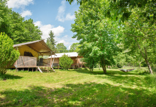 Tende safari e alberi verdi al Camping Pittoresque, un parco vacanze in Occitania, Francia, sotto il sole.