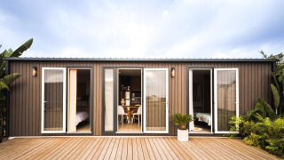 Moderna lodge di lusso con porte a vetro, terrazza in legno e piante tropicali che circondano l’area.