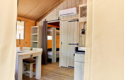 Innenansicht des Safari-Zelts Villatent Outback mit Esstisch, Etagenbett und Klimaanlage an der Wand.