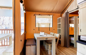 Interieur van een Villatent Outback safaritent met houten eettafel, banken en stapelbedden.