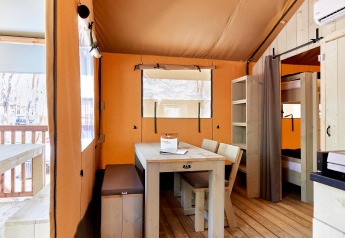 Interieur van een Villatent Outback safaritent met houten eettafel, banken en stapelbedden.