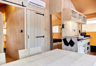 Interieur van een Villatent Outback safaritent met houten meubels, keukenblok en slaapgedeelte.
