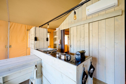 Cocina de cottage en tienda safari con paneles de madera clara en Vigna sul Mar Family Camping, Italia.