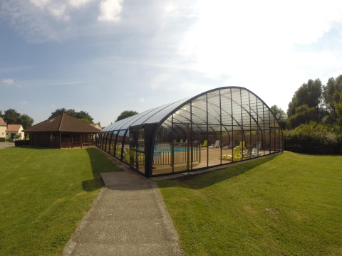 Piscina coperta e sedie a sdraio sul prato al Camping Seasonova Les Marguerites, parco vacanze in Hauts-de-France.
