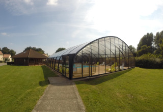Piscina coperta e sedie a sdraio sul prato al Camping Seasonova Les Marguerites, parco vacanze in Hauts-de-France.