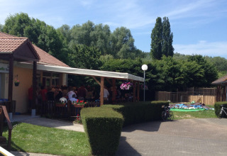 Vista esterna al Camping Seasonova Les Marguerites in Hauts-de-France con persone sotto una tettoia.