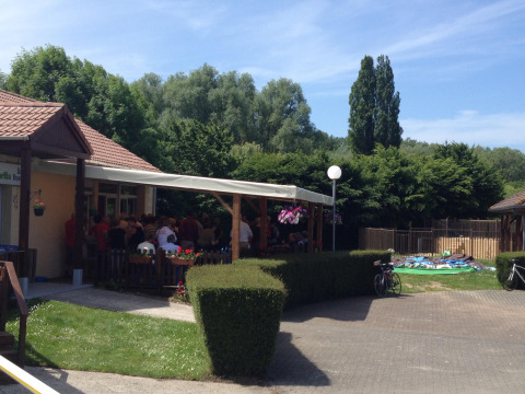 Outdoor view at Camping Seasonova Les Marguerites in Hauts-de-France with people gathered under a canopy.