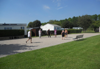 Un gruppo di persone gioca a un gioco all'aperto su ghiaia al Camping Seasonova Les Marguerites in Francia.
