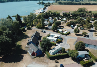 Vista aerea di Camping Seasonova Les Marguerites nei Hauts-de-France, con bungalow, roulotte e lago.