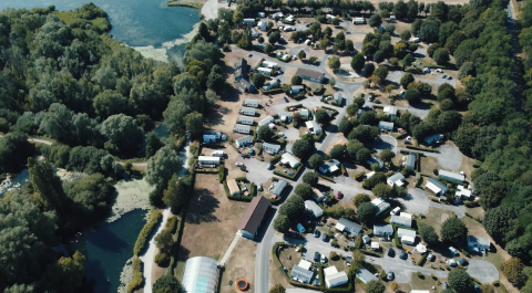 Vista aérea del Camping Seasonova Les Marguerites en Hauts-de-France, Francia, rodeado de árboles y lagos.