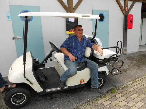 Un uomo sorridente è seduto su un golf cart al Camping Seasonova Les Marguerites, Hauts-de-France, Francia.