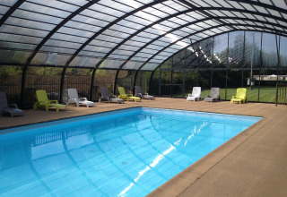 Indendørs swimmingpool med liggestole under en gennemsigtig kuppel på Camping Seasonova Les Marguerites, Frankrig.