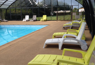 Überdachtes Schwimmbad mit Liegestühlen im Camping Seasonova Les Marguerites, Hauts-de-France, Frankreich.