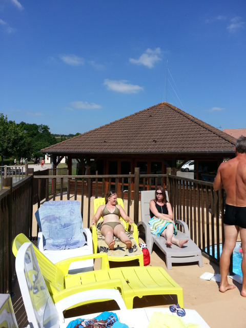 Menschen entspannen auf Sonnenliegen am Pool im Camping Seasonova Les Marguerites in Hauts-de-France, Frankreich.
