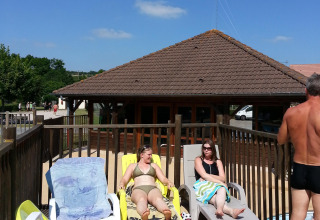People relaxing on lounge chairs by a pool at Camping Seasonova Les Marguerites in Hauts-de-France, France.