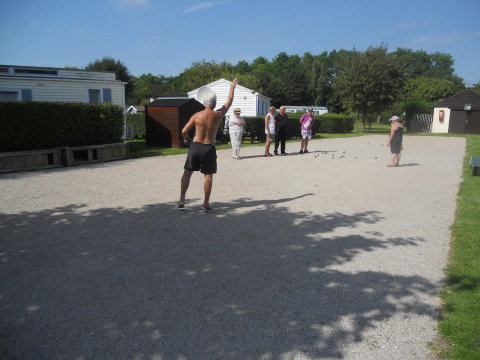 Folk spiller petanque på en grusbane i solen på Camping Seasonova Les Marguerites i Hauts-de-France, Frankrig.