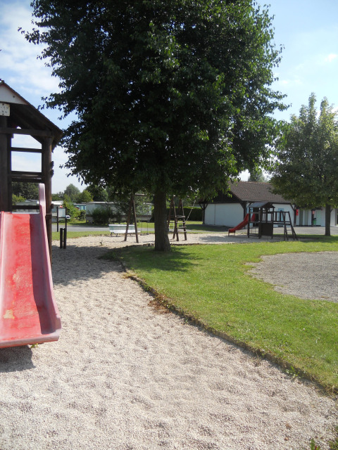 Parco giochi con scivoli, altalene e alberi presso il Camping Seasonova Les Marguerites, Hauts-de-France.