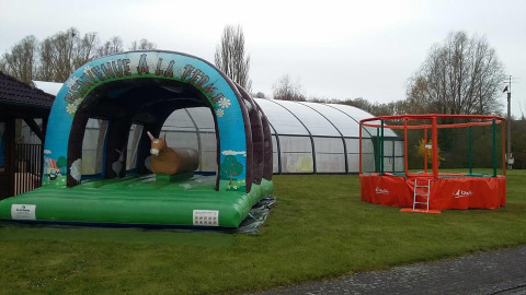 Zona de juegos inflable y trampolín en el césped del Camping Seasonova Les Marguerites, Hauts-de-France, Francia.