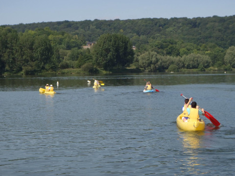 Menschen paddeln in gelben Kanus auf einem ruhigen See bei Camping Seasonova Les Marguerites in Frankreich.