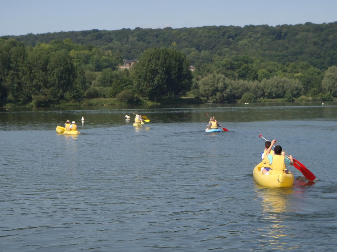 Mensen peddelen in gele kano's op een rustig meer bij Camping Seasonova Les Marguerites, Hauts-de-France.