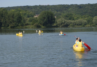 Persone che remano in canoe gialle su un lago calmo a Camping Seasonova Les Marguerites, Hauts-de-France.