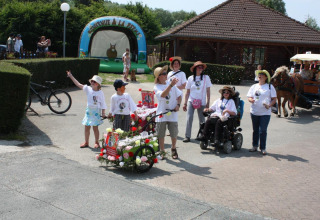 Gruppe mennesker nyder en solrig dag ved Camping Seasonova Les Marguerites, med festlige dekorationer og aktiviteter.