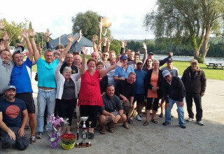 Stor gruppe campister fejrer sammen med hænderne i vejret ved Camping Seasonova Les Marguerites, Hauts-de-France.