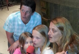 Due donne e due bambine sedute insieme con un microfono rosso al Camping Seasonova Les Marguerites in Francia.