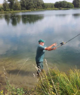Hombre pescando en el lago en Camping Seasonova Les Marguerites, Hauts-de-France, rodeado de naturaleza.