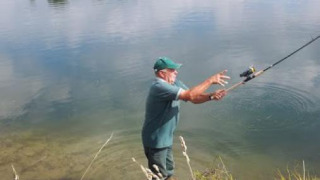 Hombre pescando en el lago en Camping Seasonova Les Marguerites, Hauts-de-France, rodeado de naturaleza.