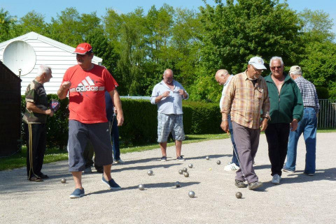 Un grupo de hombres mayores juega petanca al aire libre en Camping Seasonova Les Marguerites, Hauts-de-France, Francia.
