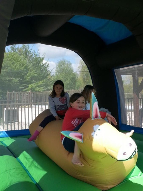 Niñas juegan en un inflable con forma de animal en un parque vacacional, rodeadas de vegetación.