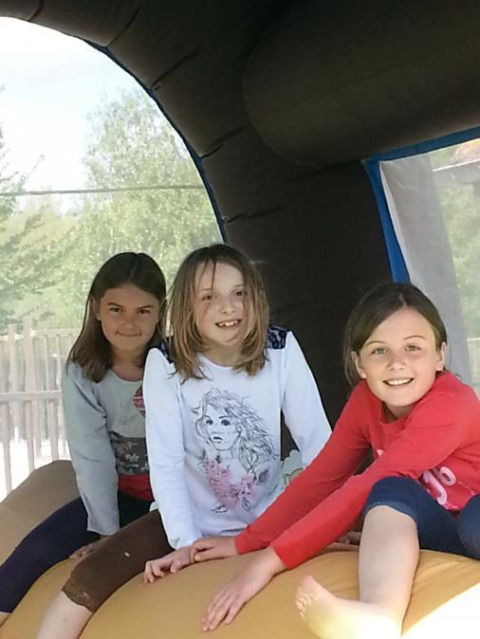Drie vrolijke kinderen spelen in een springkasteel op Camping Seasonova Les Marguerites, Hauts-de-France, Frankrijk.