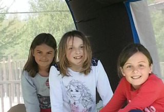 Drie vrolijke kinderen spelen in een springkasteel op Camping Seasonova Les Marguerites, Hauts-de-France, Frankrijk.