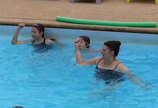 Mensen nemen deel aan een groepswateroefening in het zwembad bij Camping Seasonova Les Marguerites, Hauts-de-France.