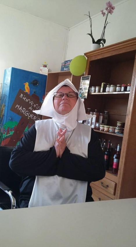 Una persona vestita da suora è seduta con le mani giunte davanti a un mobile al Camping Seasonova Les Marguerites, Francia.