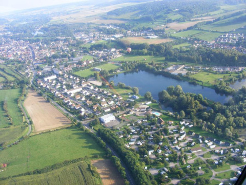 Luftfoto af Camping Seasonova Les Marguerites feriepark og sø i det grønne landskab i Hauts-de-France.