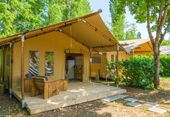 Immagine di una tenda safari chiamata Slow Lodge senza bagno, circondata da alberi e vegetazione.