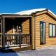 Baita in legno con tetto coperto di neve e veranda al Camping & Ferienpark Brilon, Germania, sotto cielo blu.