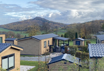 Chalets en bois au Camping & Ferienpark Brilon en Allemagne, avec collines et forêts à l’arrière-plan.