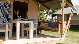 Safari tent lodge met overdekt terras en zithoek bij TinyParks Cast Away in Nederland.