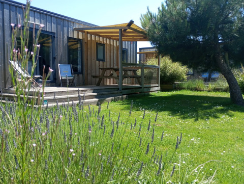 Casa Cottage Prestige en Camping Seasonova Etennemare en Francia, con terraza de madera y césped verde.