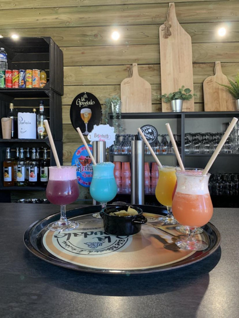 Cuatro cócteles coloridos con pajitas en una bandeja, servidos en el bar de la lodge Camping Seasonova Etennemare.